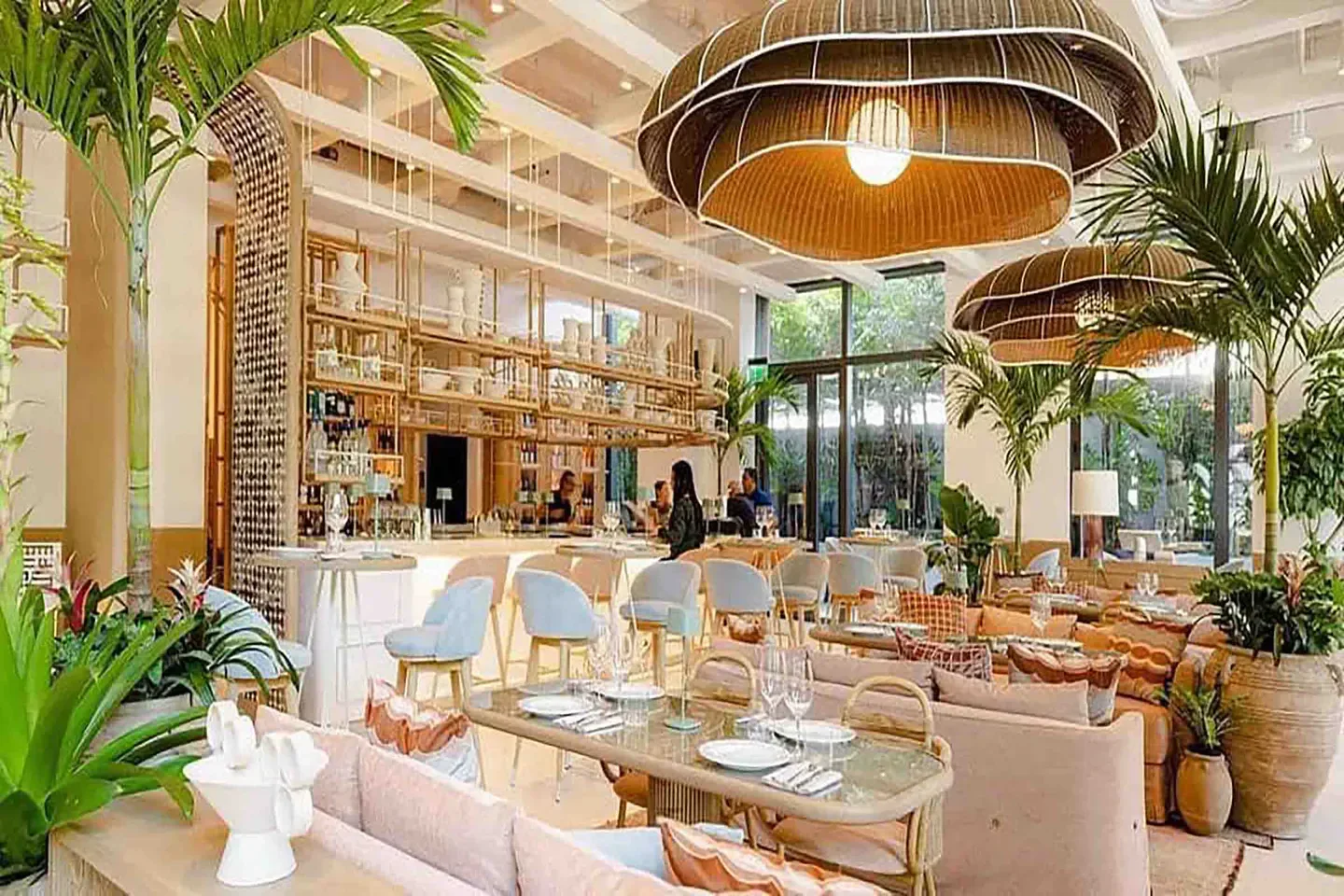 Stylish interior of Amal Miami restaurant with lush greenery and elegant decor.