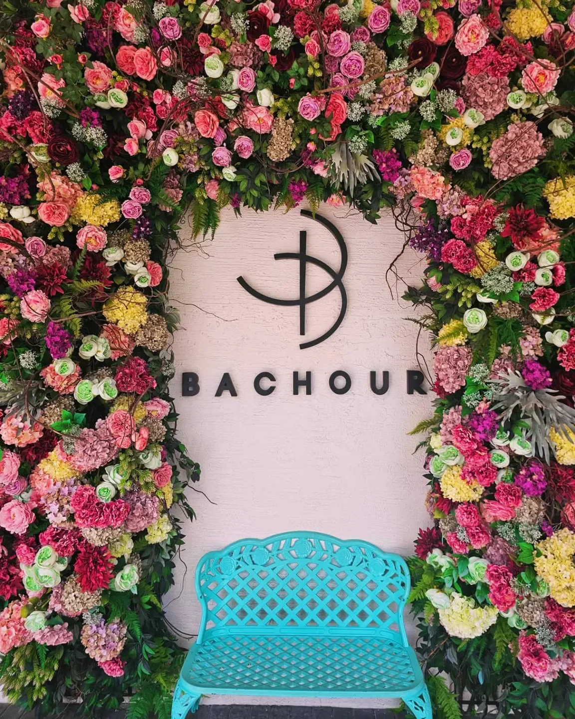 Bachour Miami with floral wall backdrop and turquoise bench, a restaurant in the city.