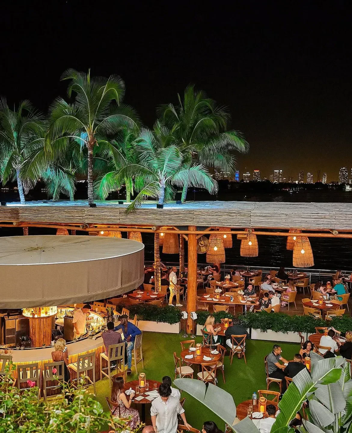 Night view of Baia Beach Club in Miami, featuring a vibrant restaurant and bar.