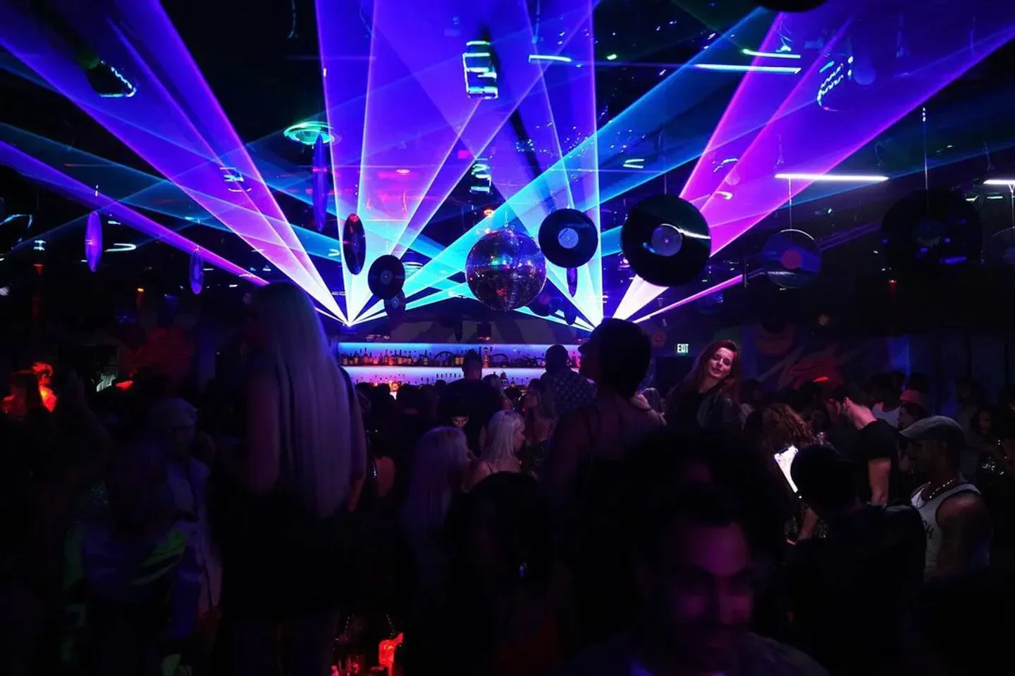 Basement Miami nightclub with laser lights, disco balls, and a vibrant party atmosphere.
