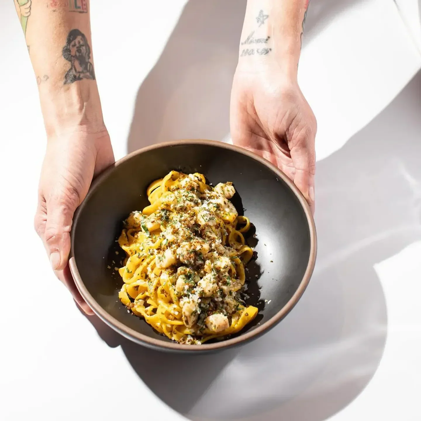 Delicious pasta dish at Boia De restaurant in Miami, served by tattooed hands