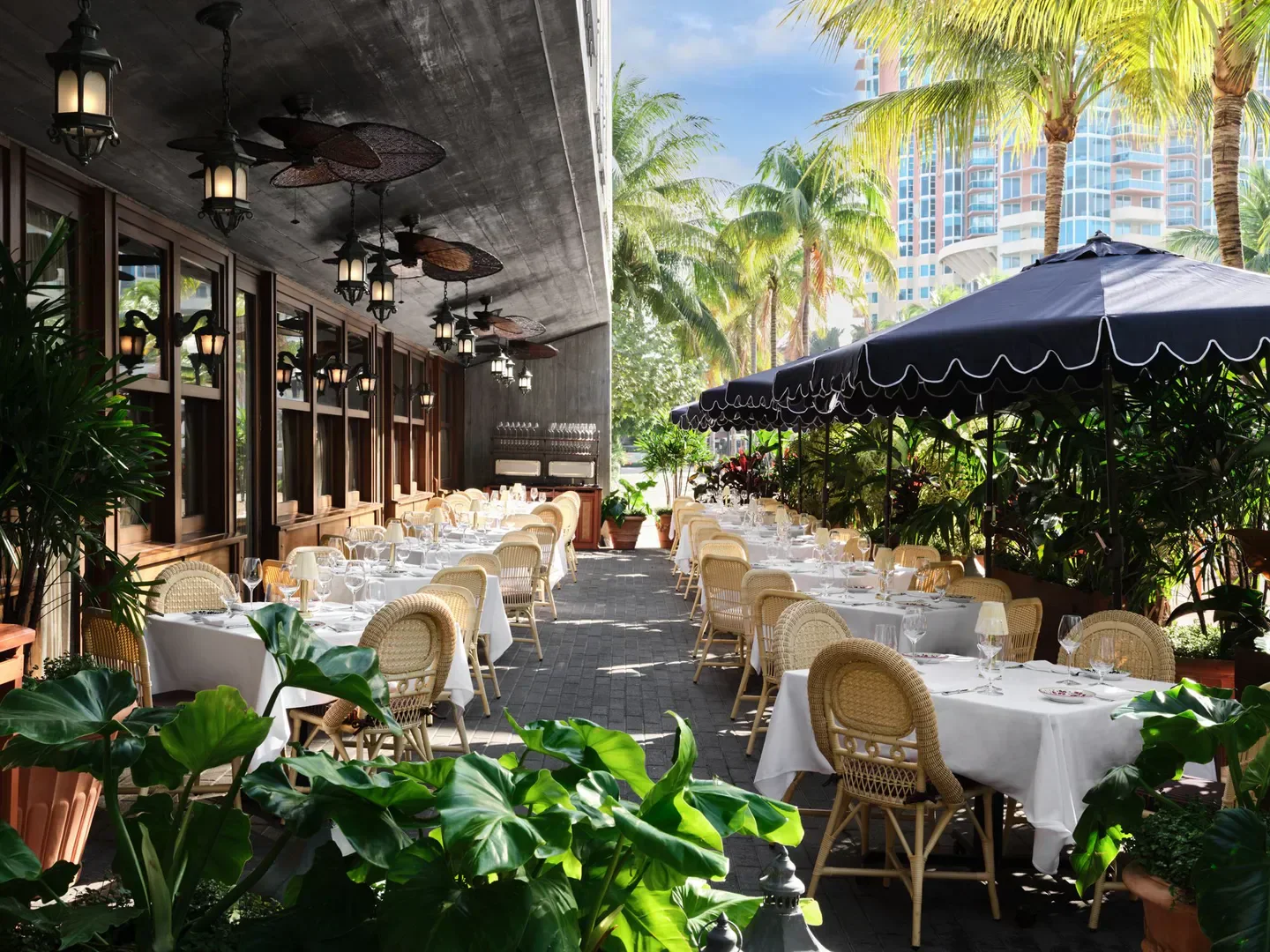 Outdoor dining at Carbone Miami, with elegant tables and lush tropical scenery