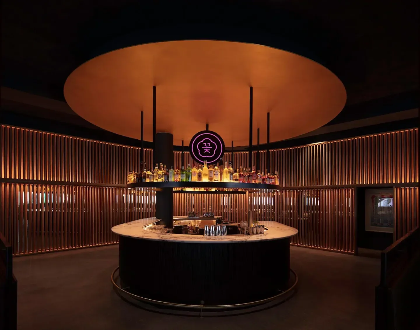 Stylish bar at COTE Miami with illuminated wood paneling and a large circular canopy