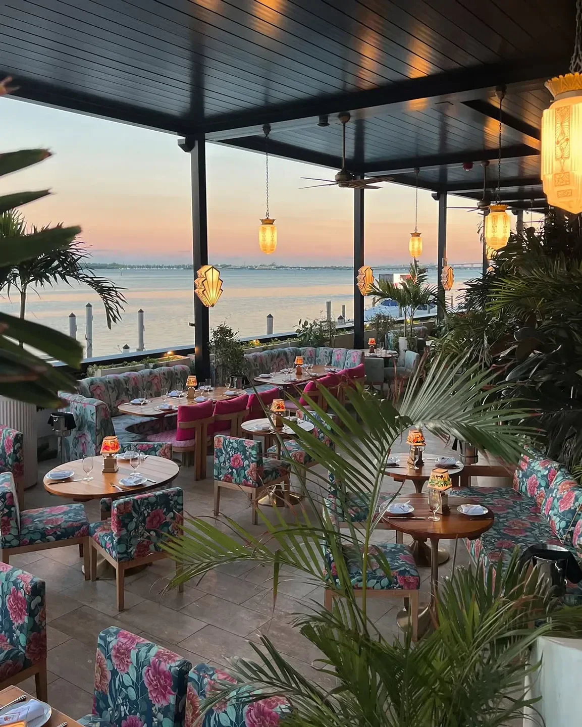 Outdoor seating at Delilah Miami restaurant, overlooking the water at sunset in Miami