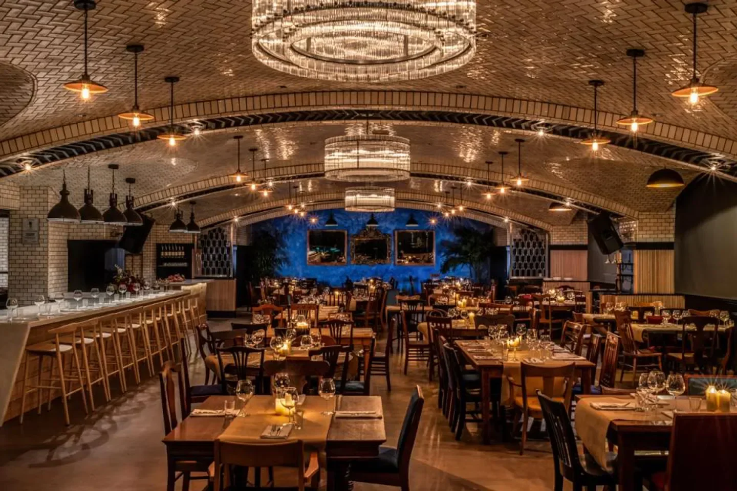 Elegant dining area at HaSalon Miami restaurant, featuring chandeliers and candlelit tables.