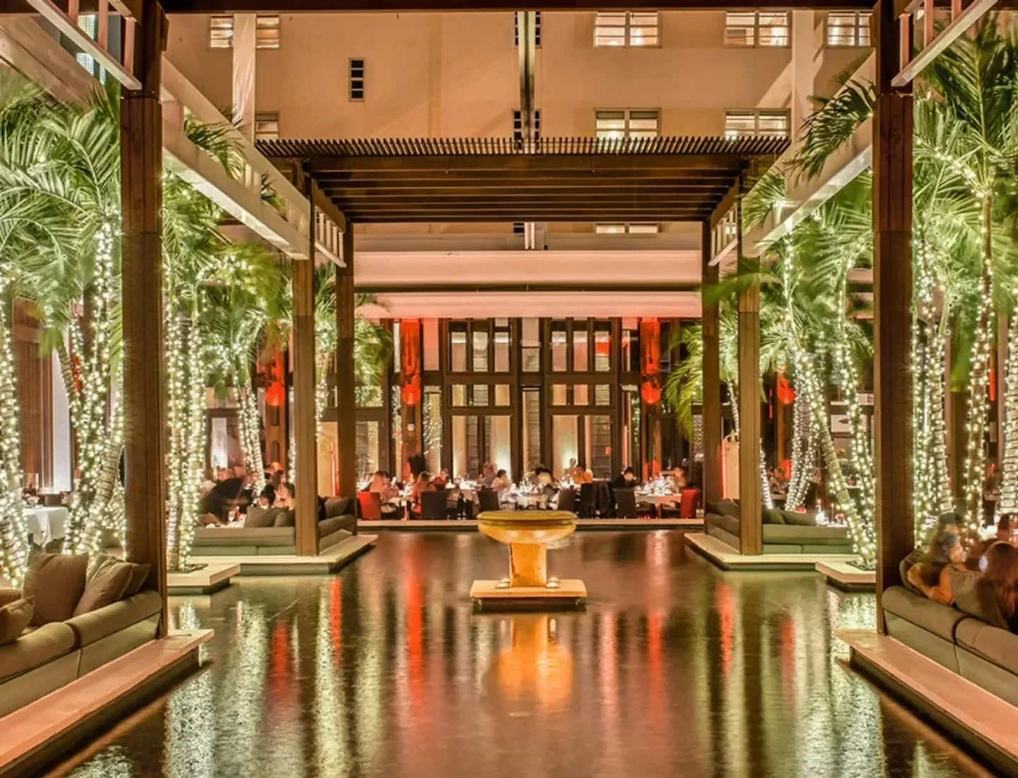 Jaya Miami restaurant's elegant outdoor dining area with palm trees and water reflection.
