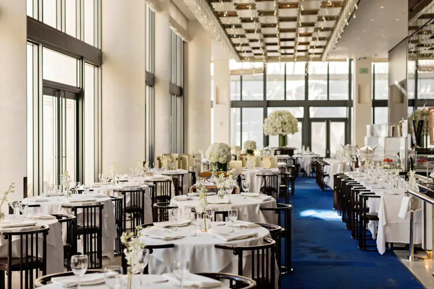 Elegant dining room interior at Mr Chow Miami, showcasing tables and floral centerpieces.