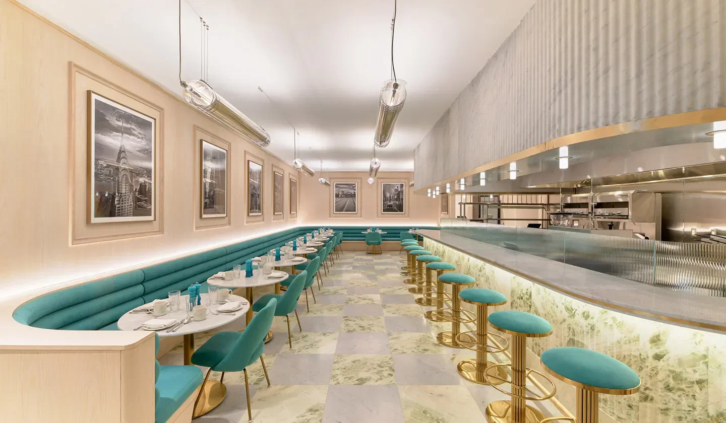 Stylish interior of Sadelle’s Miami restaurant with teal seating and elegant decor.