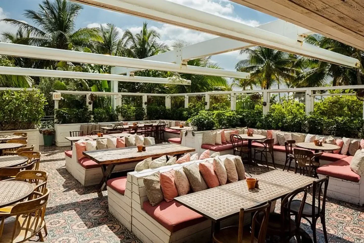Outdoor dining area at Soho Beach Club, Miami with lush greenery and cozy seating.