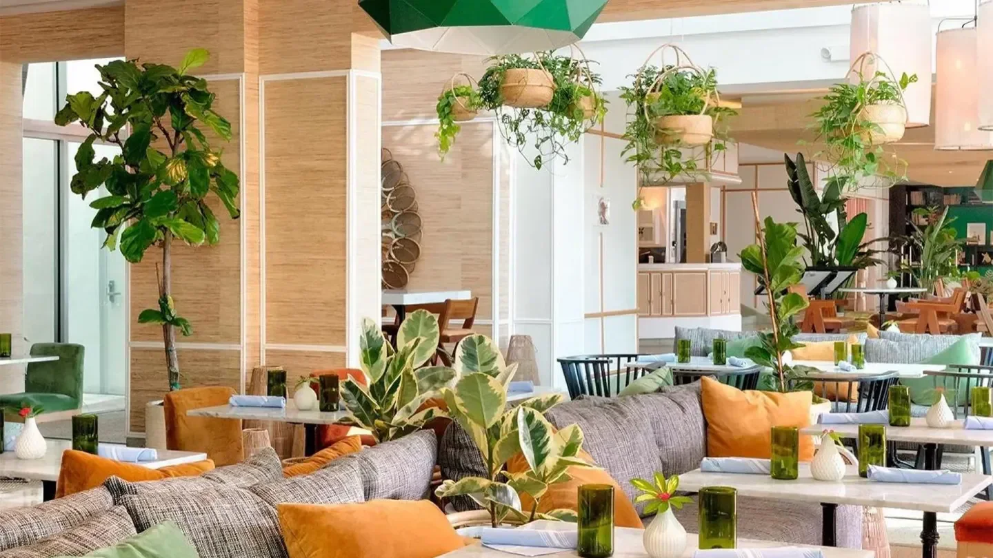 Interior of Surfcomber Pool beach club in Miami, featuring stylish decor and lush plants.