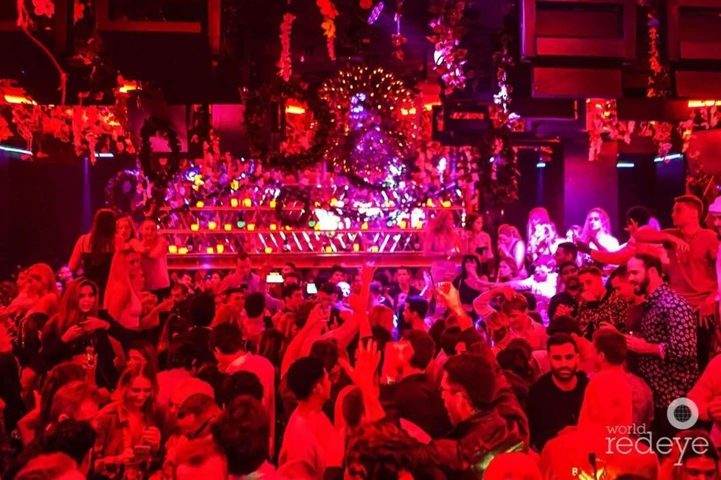 Energetic crowd partying at Wall Lounge nightclub in Miami, surrounded by lights and decor.