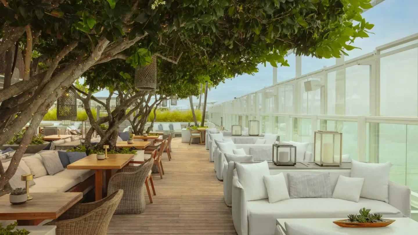 Watr at the 1 Rooftop in Miami: inviting outdoor dining area with lush trees and sofas